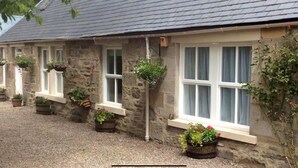 Un bâtiment en pierre doté de nombreuses fenêtres, dont certaines sont ornées de jardinières suspendues.