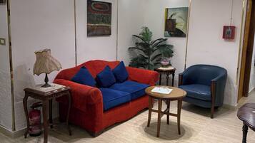 A modern living room with a red sofa, a blue armchair, and a small round table.