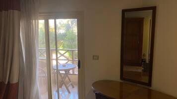 A room with a sliding glass door leading to an outdoor patio with a table and chairs. There is a wooden dresser and a mirror on the wall.