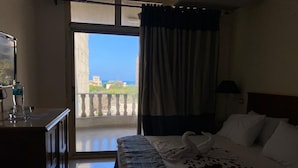 A hotel room with a bed, a desk, and a view of the sea. - Bianchi Hotel (Alexandria)
