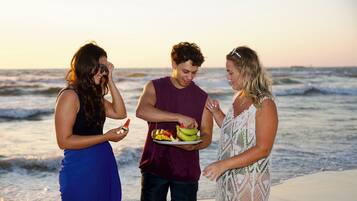 Three people on a beach with a plate of fruit.