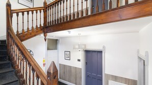 Uma escada de madeira com uma parede branca e uma porta azul ao fundo.