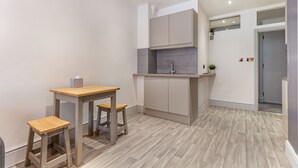 Uma cozinha compacta com mesa e banquetas de madeira, pia embutida e bancada pequena.