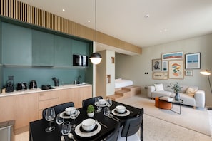 A modern living room with a sofa, coffee table, and dining area with a table set for a meal.