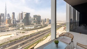 Habitación de hotel moderna con un balcón grande, ofreciendo vistas de un paisaje urbano con rascacielos y una autopista.