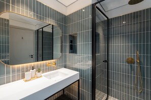 A modern bathroom with a white sink, a large mirror, and a glass-enclosed shower area. - Sleek Business Bay Studio, Burj View Balcony (Dubai)