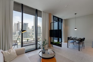 A modern living room with a large window, a dining area, and a sofa.