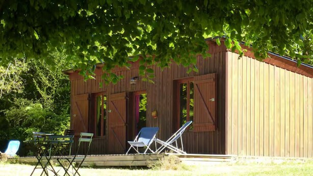 Una baita di legno con veranda, due poltrone e un tavolo.