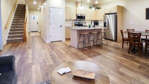 A modern kitchen with a central island, stainless steel appliances, and a dining area with wooden chairs. - Modern Family Townhome Near Downtown Caldwell | Sleeps 10 (Caldwell)