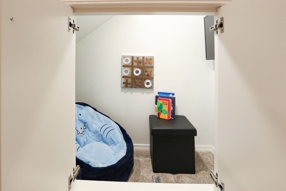 A small, enclosed bathroom with a blue pet bed, a wall-mounted toilet paper holder, and a box of 'Dinosaur' themed toilet paper.