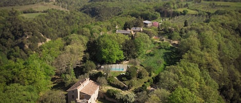 Propiedad rural con una casa rodeada de abundante vegetación, piscina y paneles solares.