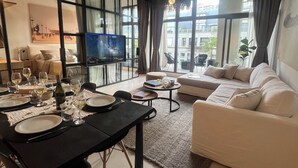 Un salon moderne avec un coin repas, de grandes fenêtres et un téléviseur.