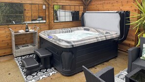 Un bain à remous avec une terrasse en bois, un espace salon et une fenêtre.
