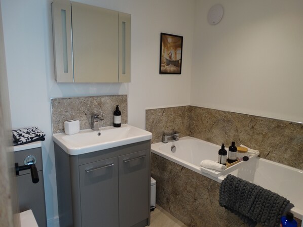 Een moderne badkamer met een marmeren wastafel, een badkuip en een toilet.