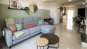 Una sala moderna con un sofá seccional gris, una mesa de centro redonda y un comedor con una mesa y sillas.