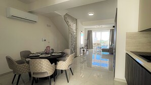 Un comedor moderno con una mesa redonda, sillas y una zona de cocina con mostrador.