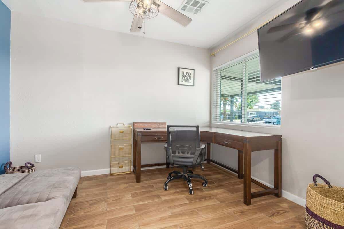 Ein Zimmer mit Schreibtisch, Stuhl, Bett und Fernseher.