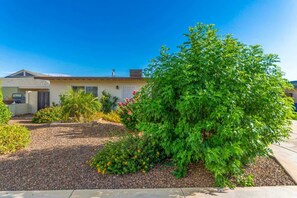 A residential house with a well-maintained garden, a driveway, and a garage.