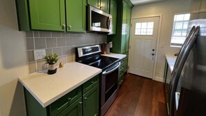A kitchen with green cabinets, a microwave, an oven, and a refrigerator.