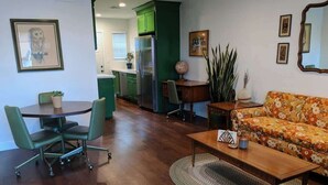 A living room with a sofa, coffee table, and a dining area with chairs and a table.