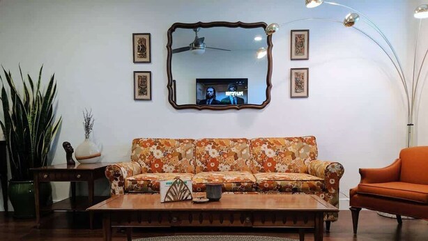 A living room with a floral sofa, a wooden coffee table, and a round rug.
