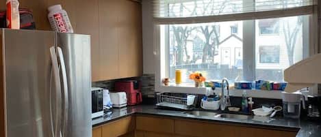 A kitchen with a stainless steel refrigerator, a microwave, and a sink.