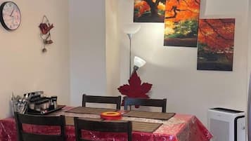 Un coin repas avec une table dressée pour quatre personnes, un ventilateur de plafond et des œuvres d’art accrochées aux murs.
