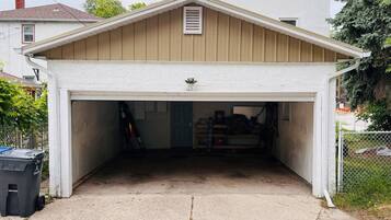 A garage with a white roof and wooden siding, a door, and a concrete floor.