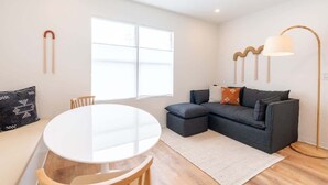 A modern living room with a round white table, a dark grey sofa, and a floor lamp. - Cozy Beachside Stay w/King Bed & Modern Comforts (Miami Beach)