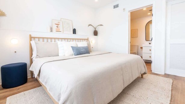 A bedroom with a bed, bedside tables, a mirror, and a door. - Cozy Beachside Stay w/King Bed & Modern Comforts (Miami Beach)