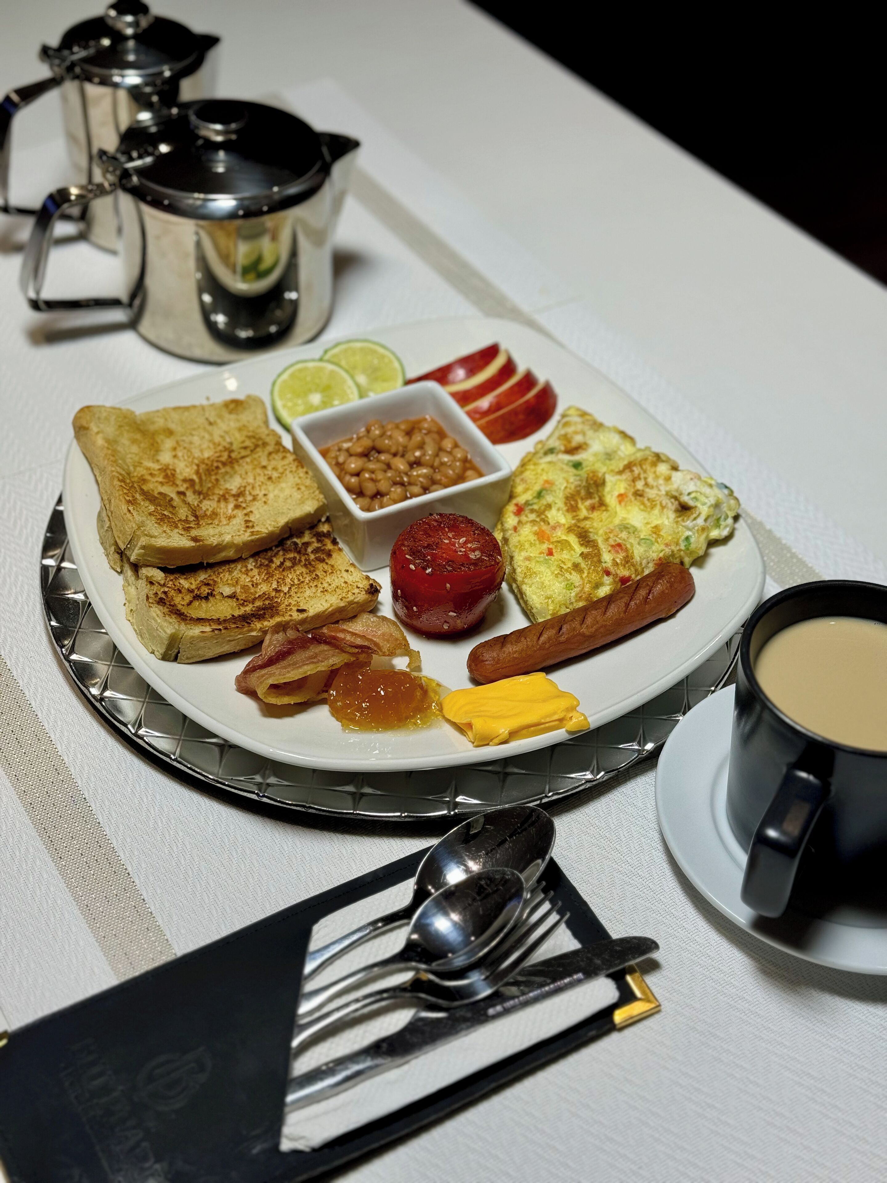 Un plato de desayuno con tostadas, frijoles, tomate, rodajas de manzana y una tortilla.
