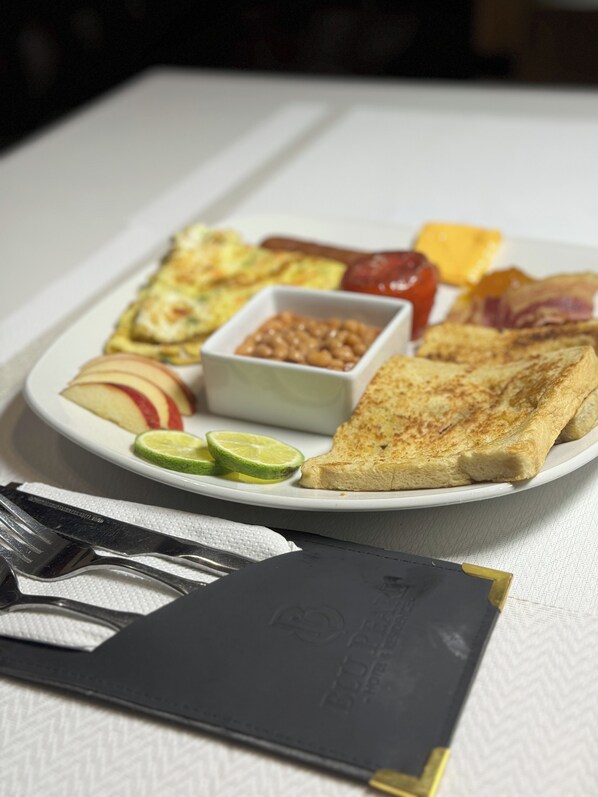 A plate of breakfast food including toast, eggs, bacon, and fruit. - Blu Pearl Hotel & Residence (Benin City)