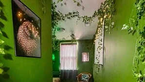 Un couloir étroit aux murs verts, doté d’un plancher en bois et orné d’un tableau représentant un léopard.