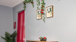 Une pièce avec un bureau en bois, une plante en pot et un rideau rouge.
