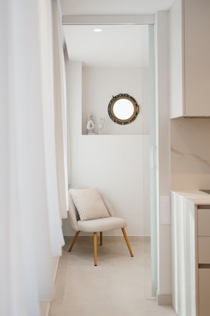 Un pasillo estrecho con una silla y un espejo en la pared.