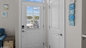 A room with a white door, a small wooden side table, and a wall-mounted decoration. - Seaside Villa w/ elevator 3bedroom~5Beds~Sleeps 8 (Atlantic Beach)