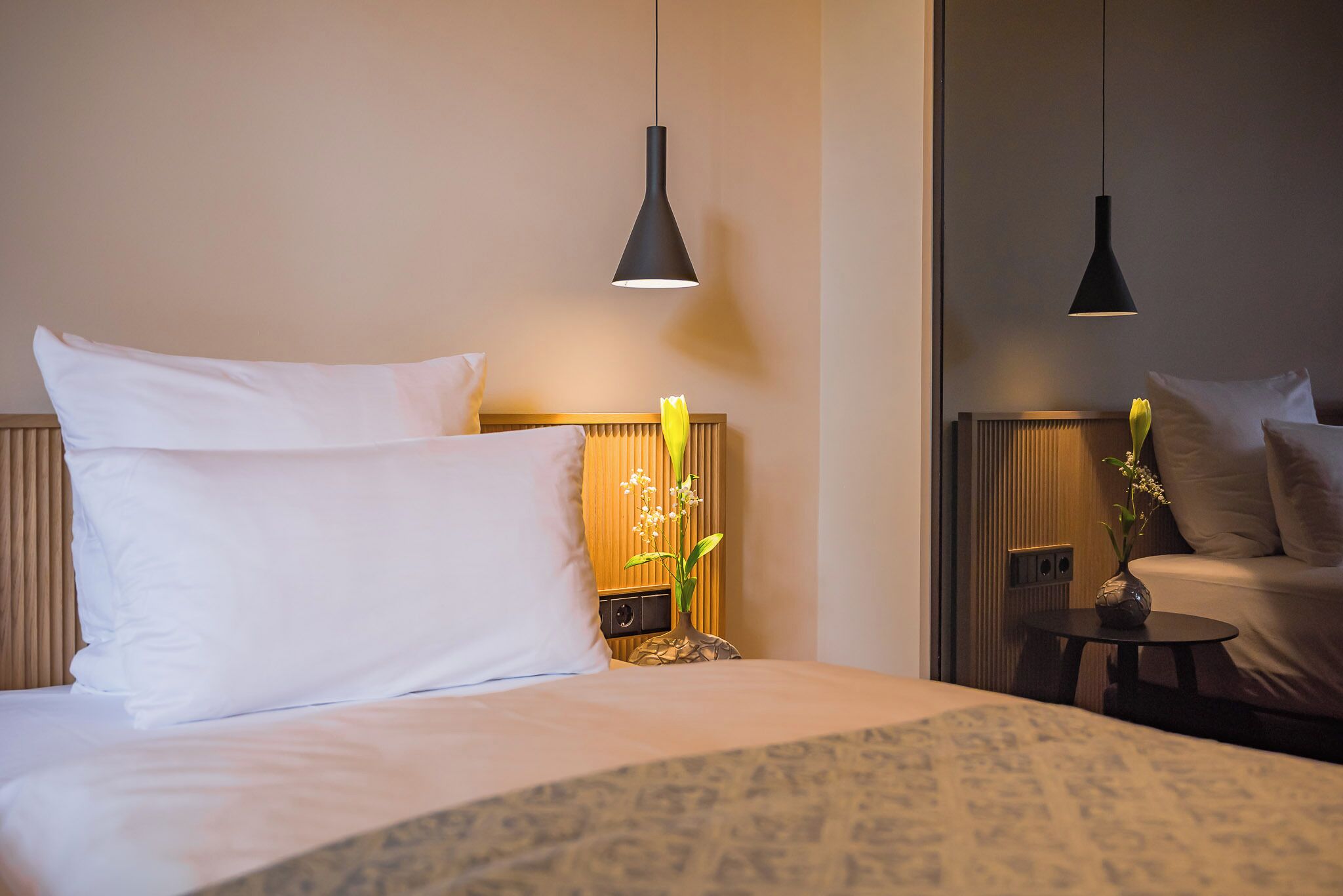 Una habitación de hotel con cama, mesitas de noche y lámparas colgantes.