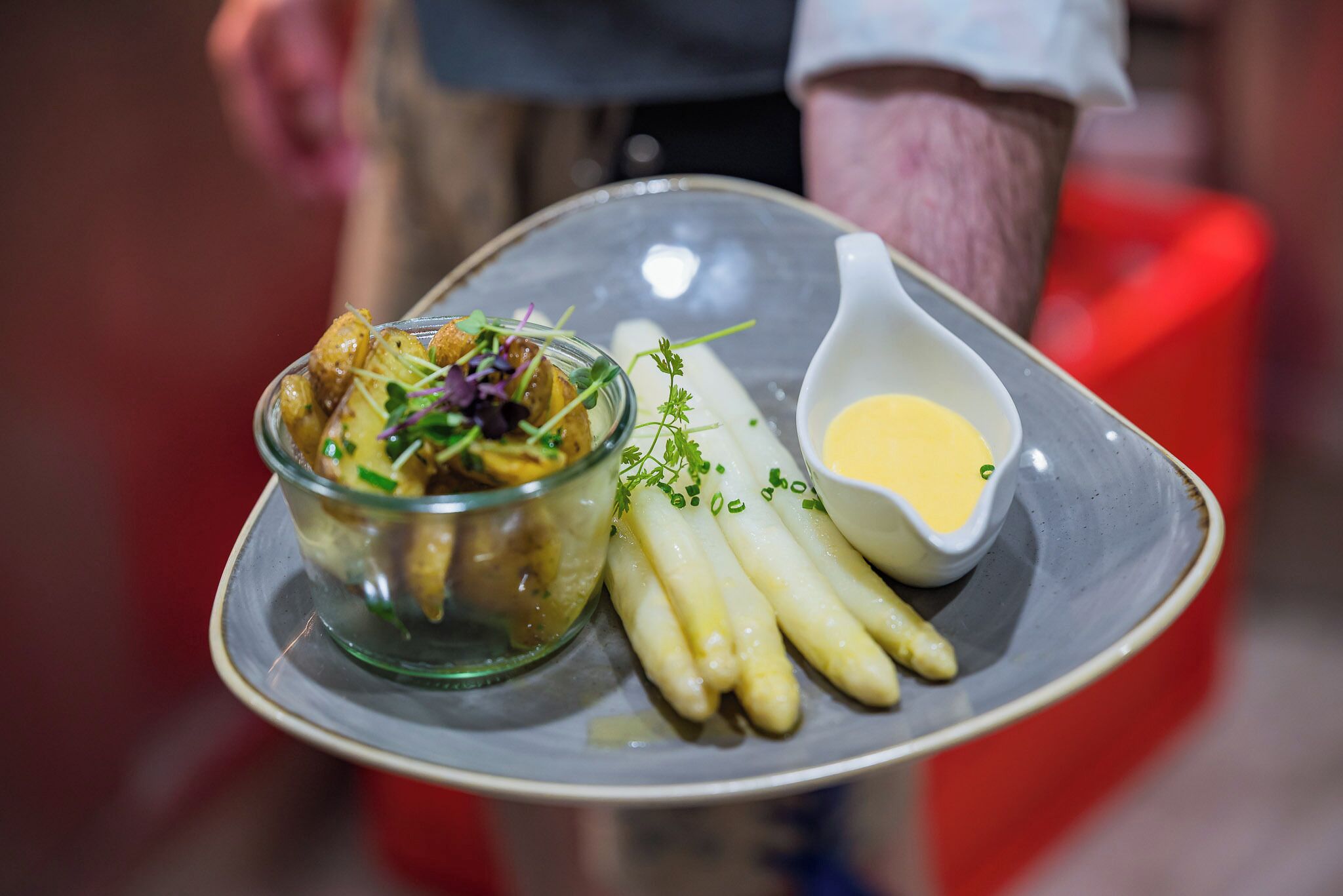 Une assiette avec une salade, des asperges et un petit bol de sauce.