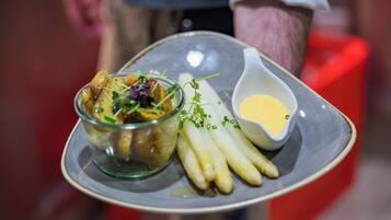 Une assiette avec une salade, des asperges et un petit bol de sauce.