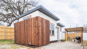 A modern house with a wooden exterior, a gravel driveway, and a barbecue area. - Modern Tiny Home 15 mins from Fort Worth (Fort Worth)