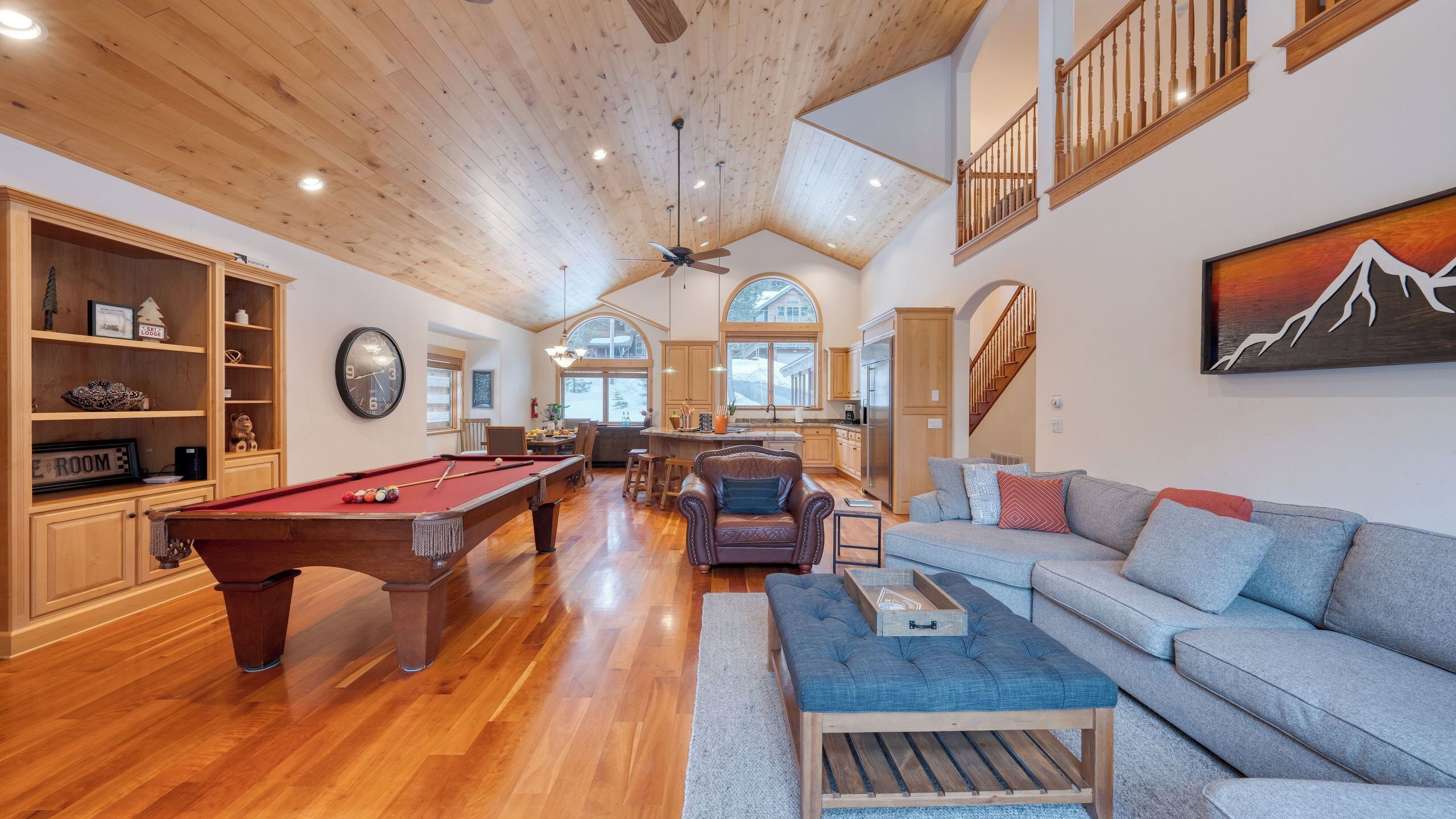 A spacious living area with a pool table, a sofa, and a dining area.