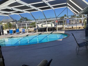 A pool area with a clear blue pool, lounge chairs, and a covered seating area.