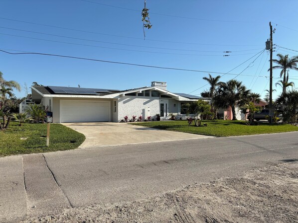 A single-story house with a garage, solar panels, and a well-maintained lawn.