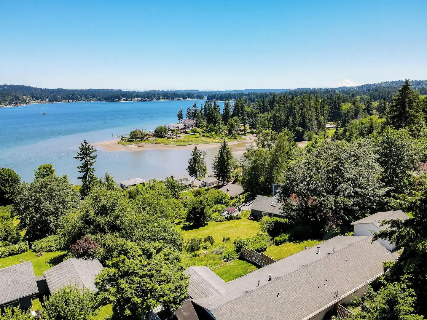 A residential area with houses, a lake, and a forested hill in the background.