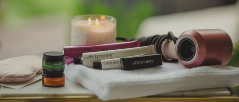 A table with skincare products, a candle, and a hairdryer.
