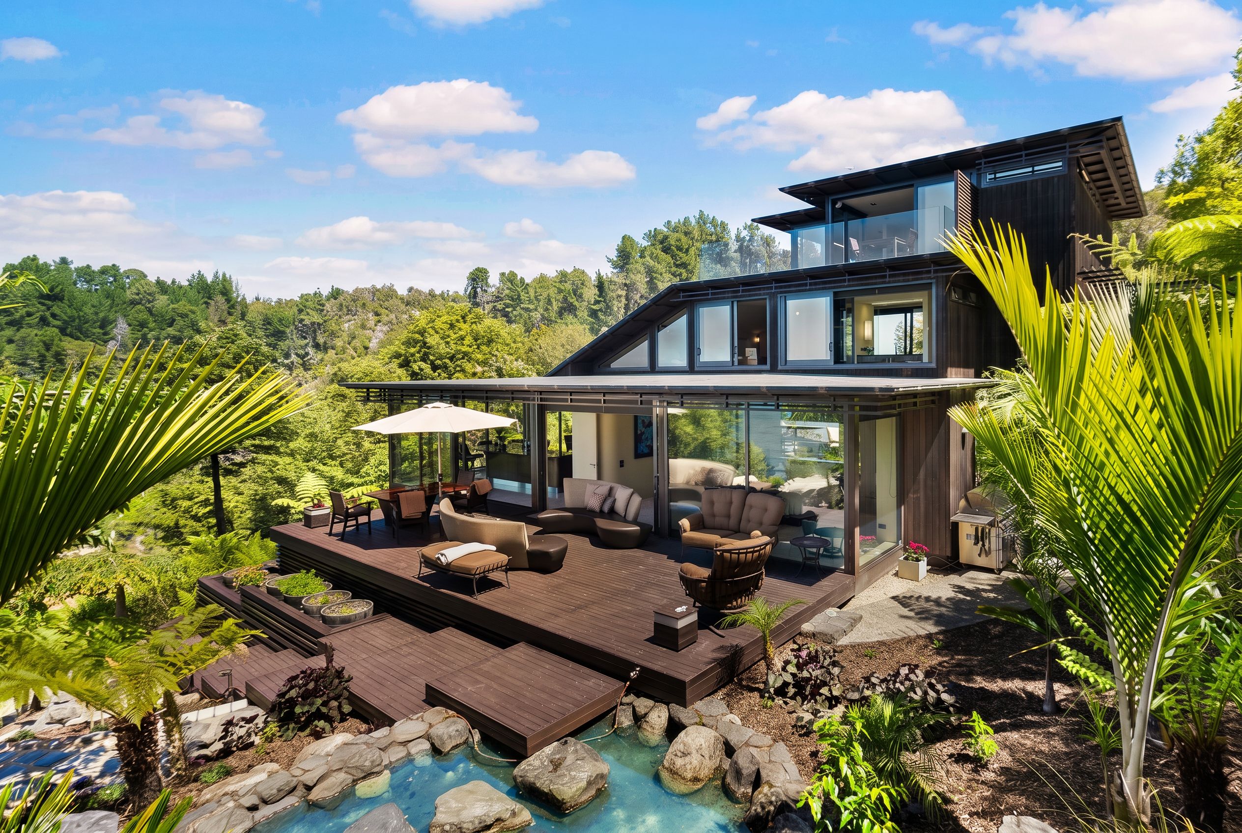 Ein modernes, zweistöckiges Haus mit einer großen Terrasse, Sitzgelegenheiten im Freien und einem Swimmingpool.