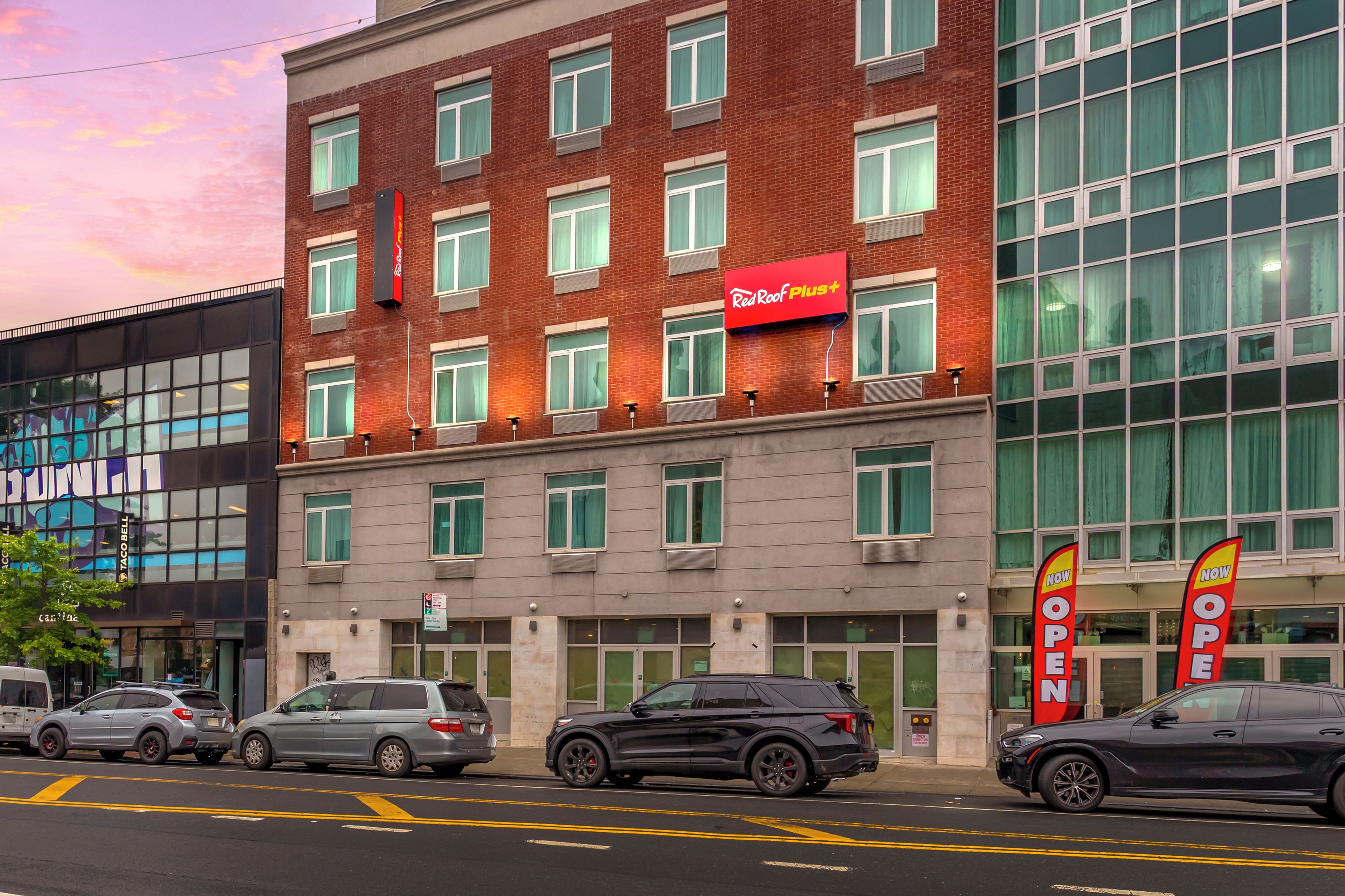 A multi-story hotel with a red and white sign indicating a Red Roof Plus+ brand.