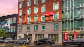 A multi-story hotel with a red and white sign indicating a Red Roof Plus+ brand.