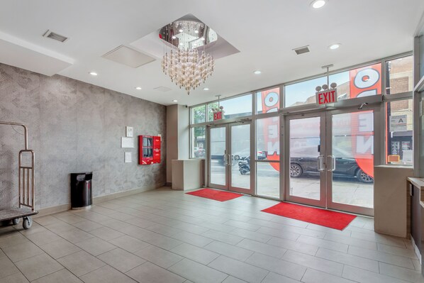 A hotel lobby with a patterned wall, a chandelier, and a view of the street through the entrance doors. - Red Roof PLUS+ Brooklyn - Flatbush Ave (Brooklyn)