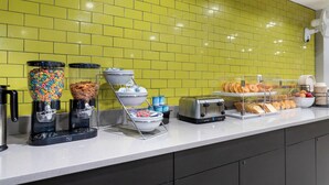 Una barra de desayuno con dispensadores de cereales, una máquina de café y un tostador.